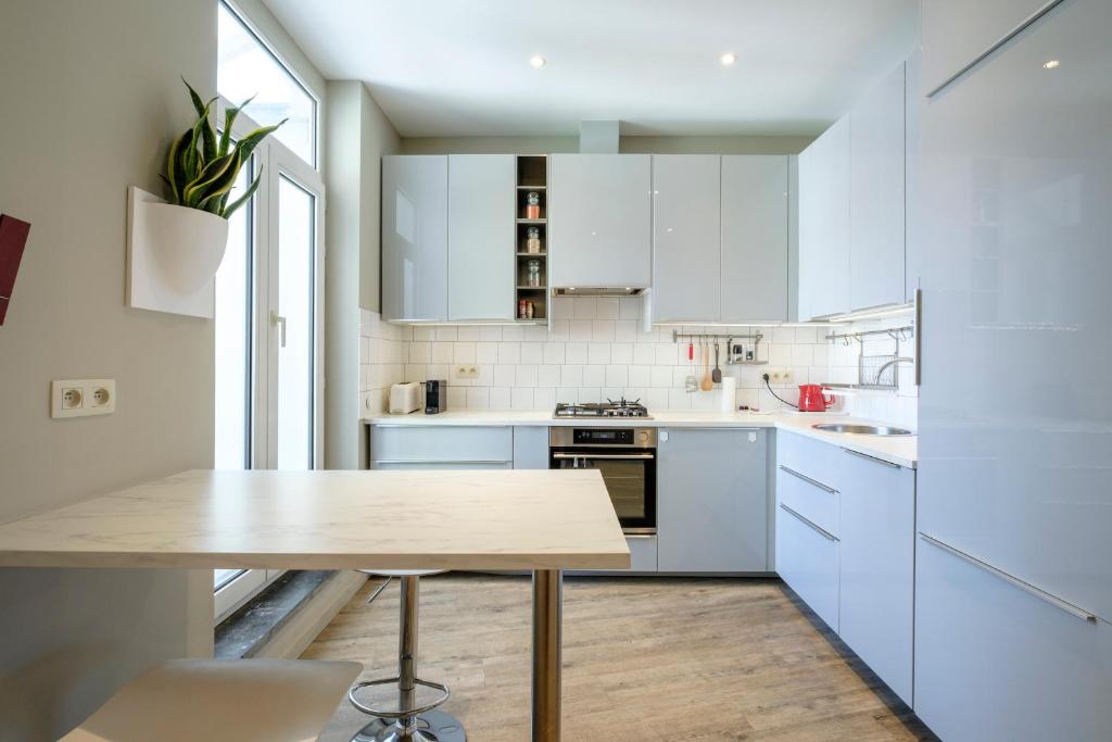 a kitchen with white cabinets and a wooden table at Charmant Appartement 1 chambre avec balcon proximité Cinquantenaire in Brussels