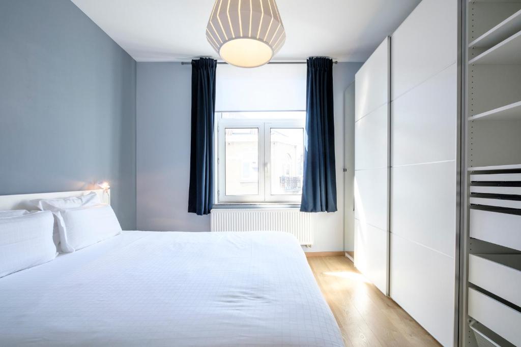 a bedroom with a white bed and a window at Charmant Appartement 1 chambre avec balcon proximité Cinquantenaire in Brussels