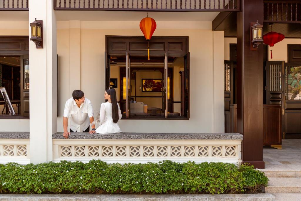 a bride and groom standing on the front of a building at Wyndham Garden Hoi An Cua Dai Beach in Hoi An