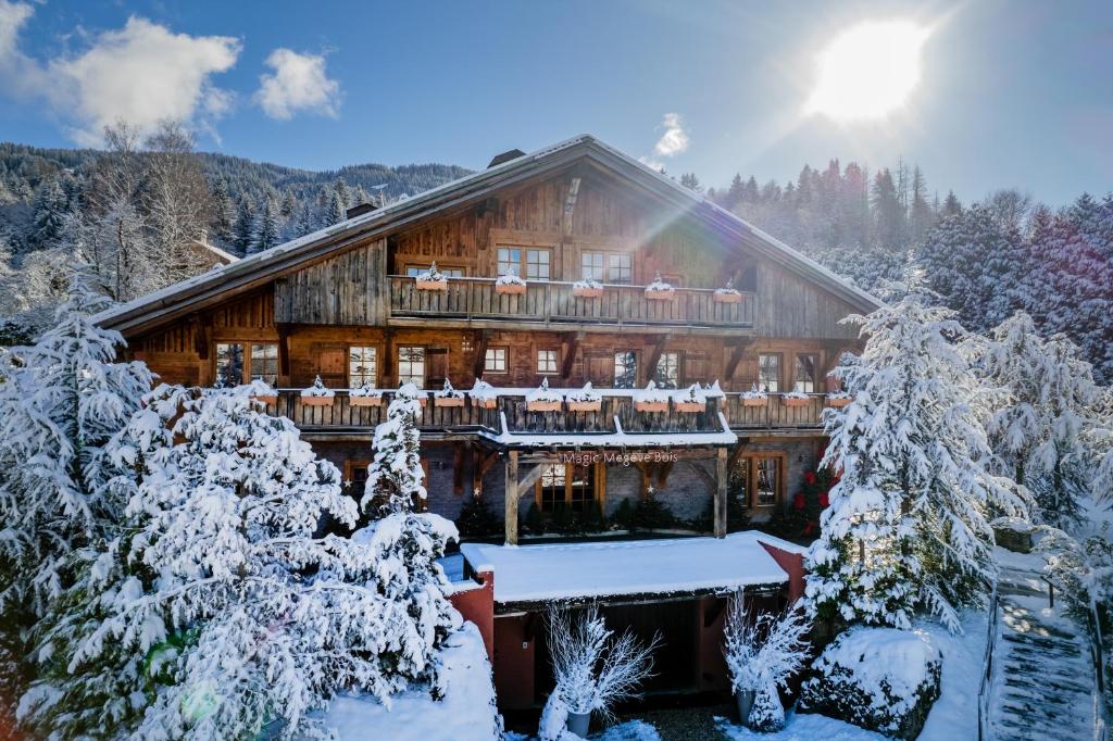 una baita di tronchi nella neve con alberi di Magic Megève Bois a Demi-Quartier