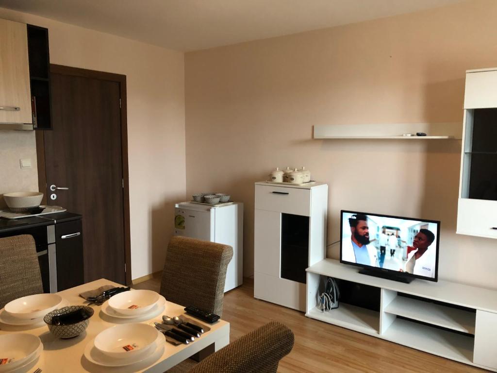 ein Wohnzimmer mit einem Tisch und einem TV in der Unterkunft Palace De Luxe - Apartments in Pomorie