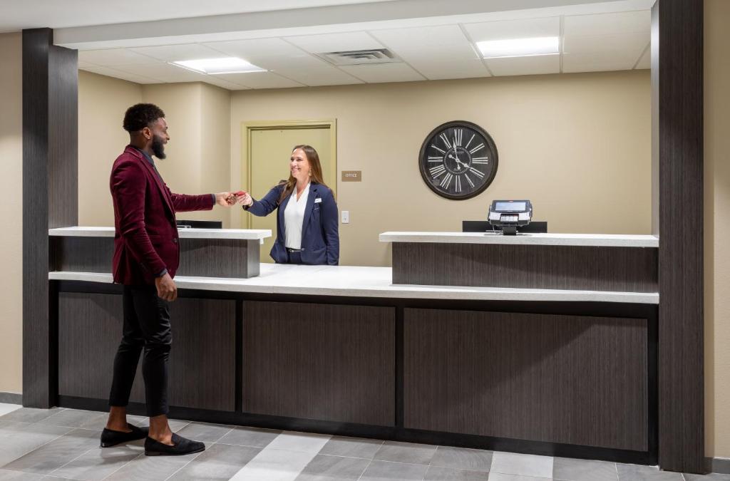 a man and woman shaking hands at a reception counter at Candlewood Suites - Rochester Mayo Clinic Area in Rochester