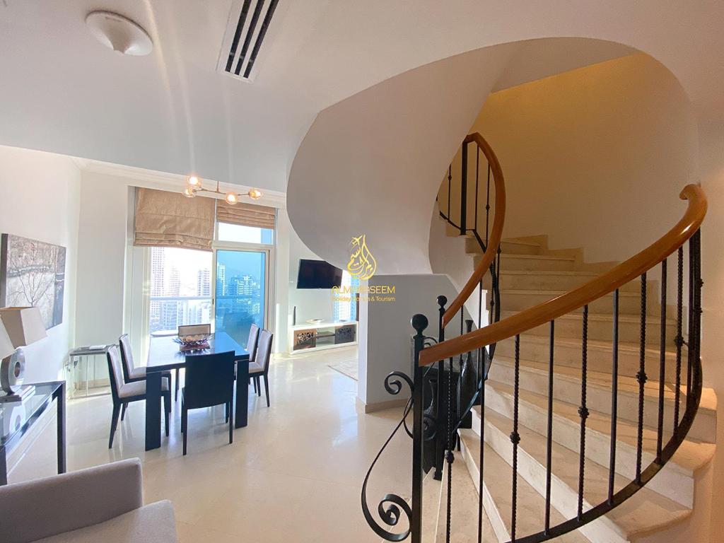 a spiral staircase in a living room with a dining table at Dorra Bay Tower Dubai Marina - AL Maraseem in Dubai