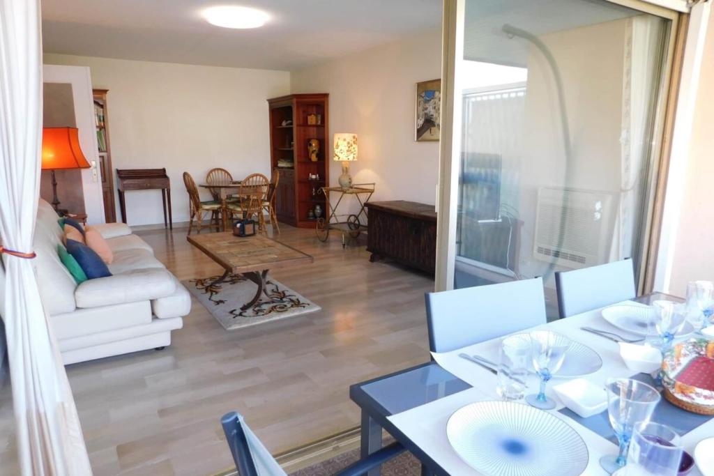 a living room with a table and a couch at Spacious T2 "Jardin du Pont du Lys" with pool and parking in Antibes