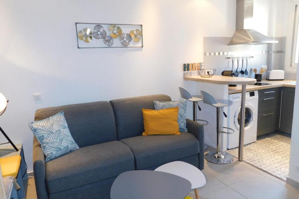 a living room with a blue couch and a kitchen at T1 "Santa Luccia" with air conditioning in Saint-Laurent-du-Var