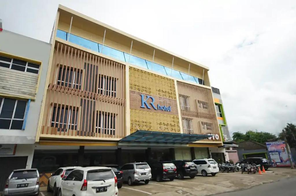 un gran edificio con coches estacionados frente a él en TwoSpaces Living at KR Hotel, en Palembang