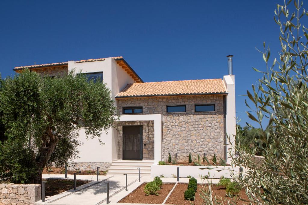 uma casa com uma fachada de pedra e uma árvore em Olive green villas em Lefkada