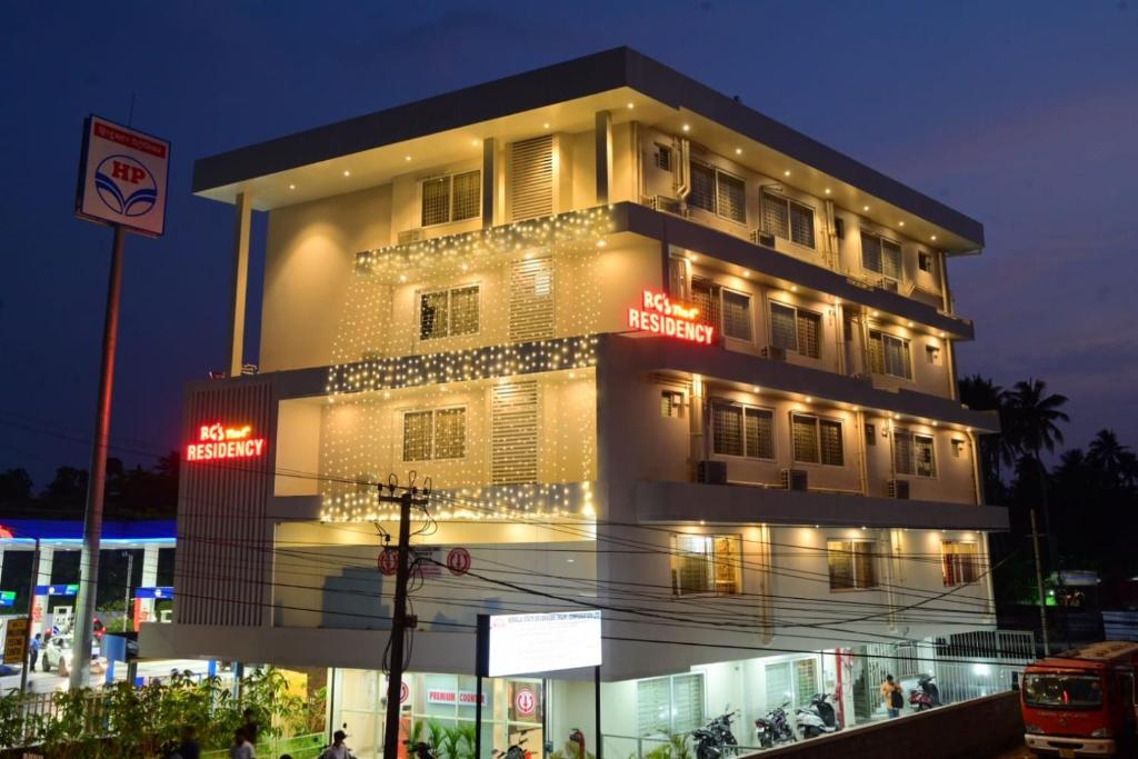 - un grand bâtiment avec des panneaux de néon la nuit dans l'établissement RG's The 4th Residency, à Trivandrum