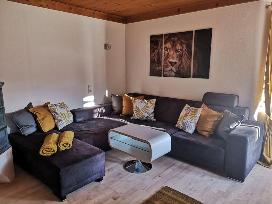 una sala de estar con un sofá de cuero negro y una pintura del león en Tiroler Wohnung, en Arzl im Pitztal