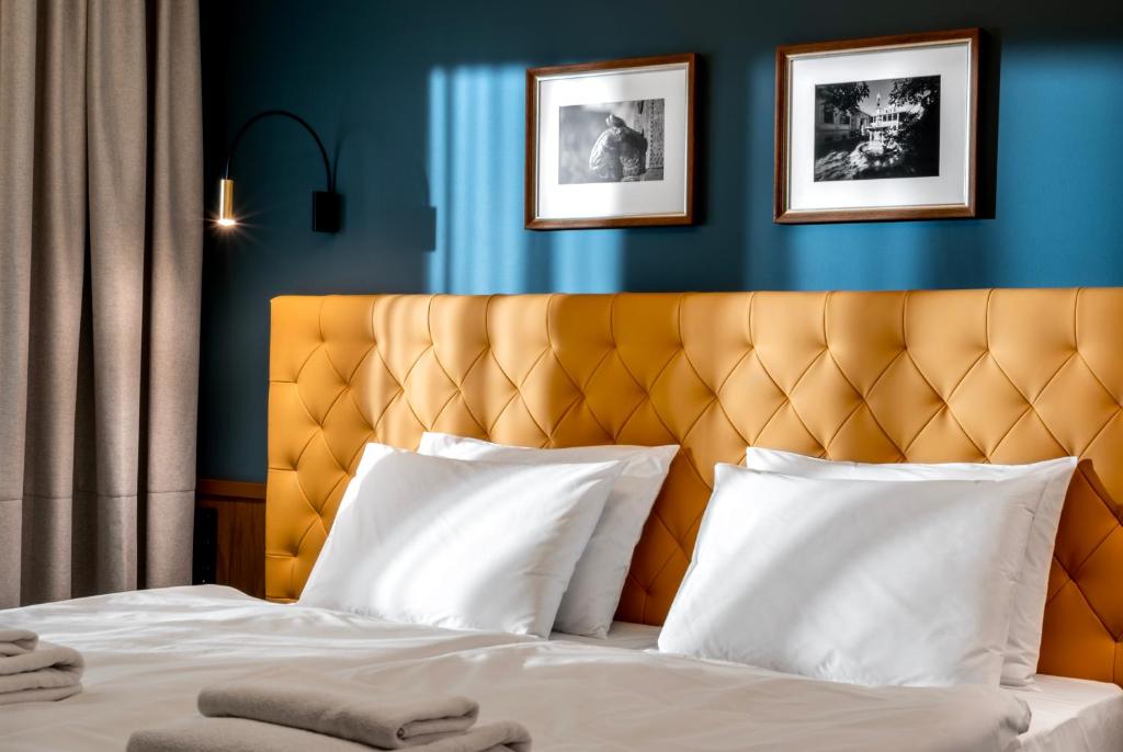 Palatinus Boutique Hotel في بيتْش: غرفة نوم بسرير مع اللوح الأمامي الأصفر