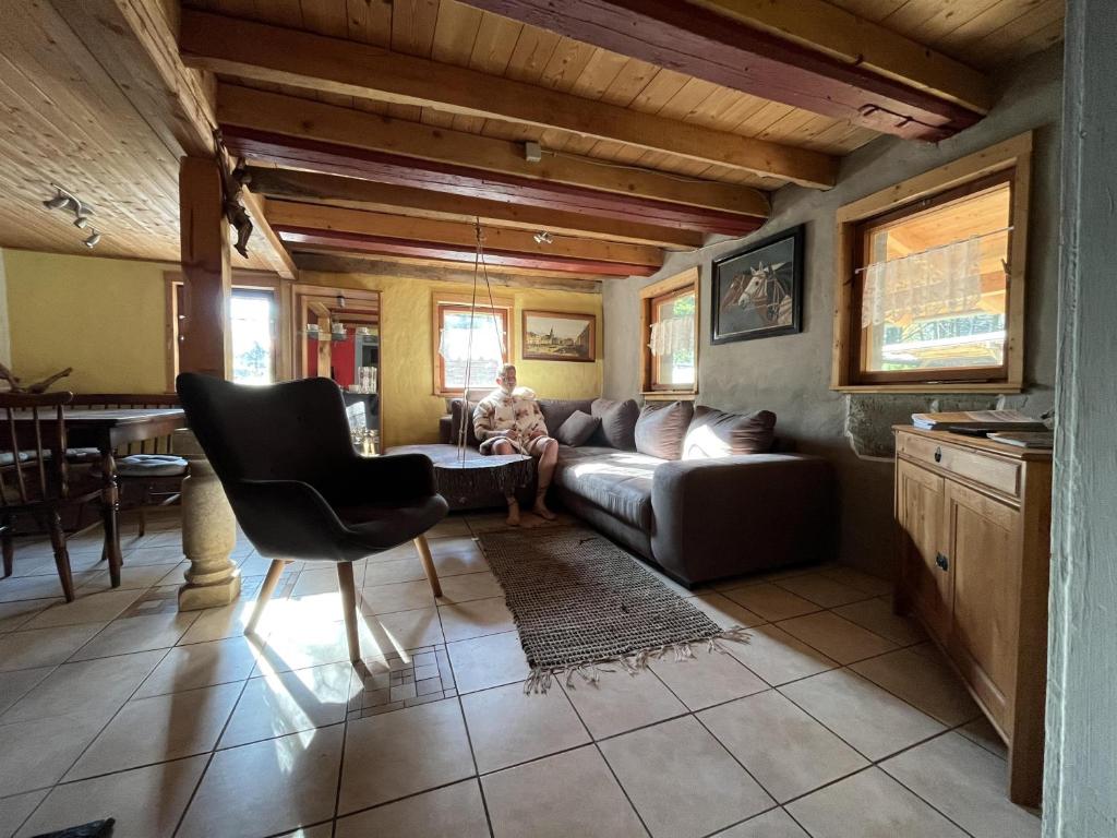 a woman sitting on a couch in a living room at Ferienwohnung "An der schönen Bahra" in Bahra