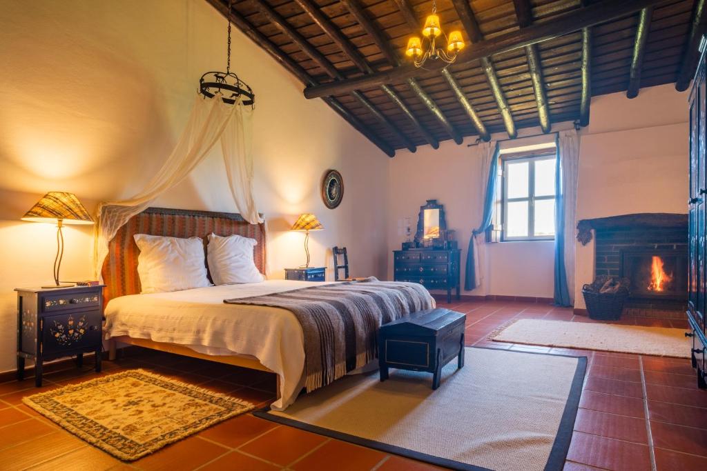 een slaapkamer met een groot bed en een open haard bij Monte das Lages in Redondo