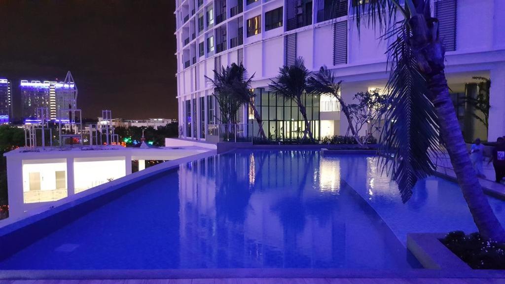una piscina di fronte a un edificio di notte di LAVENDER Suite @ I-City a Shah Alam