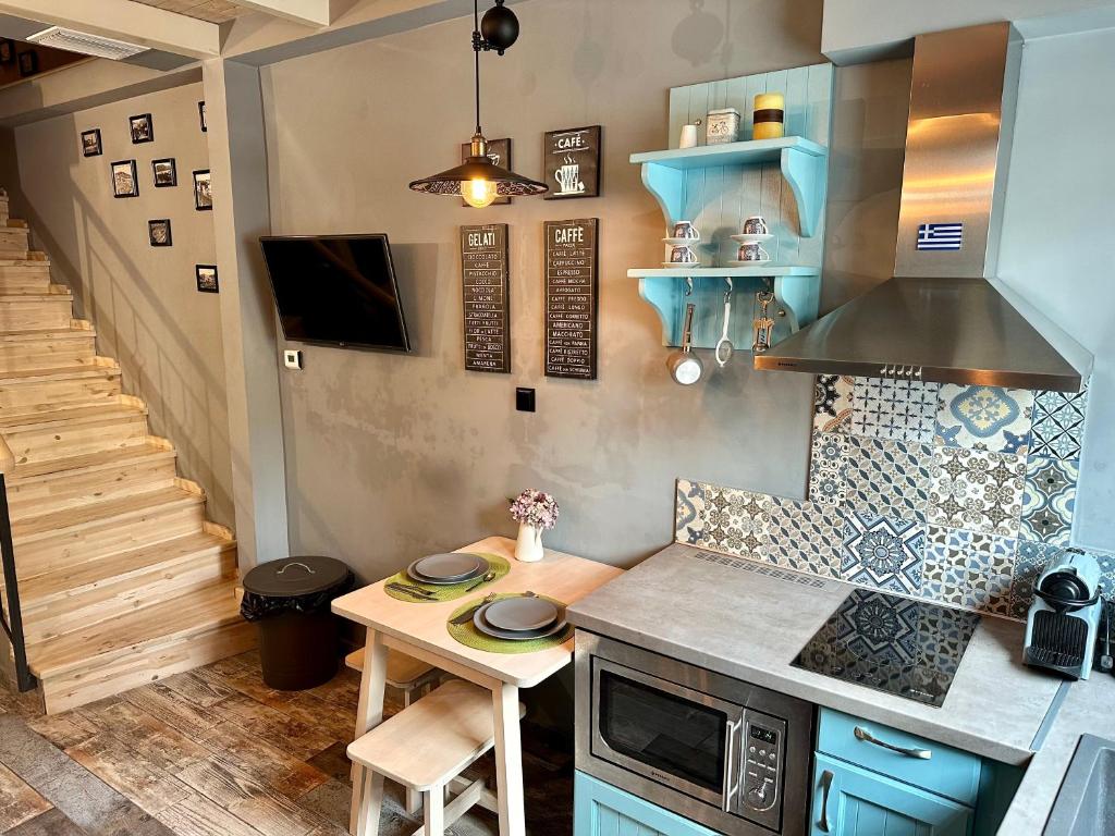 uma cozinha com armários azuis e uma pequena mesa em Kamares View em Kavala