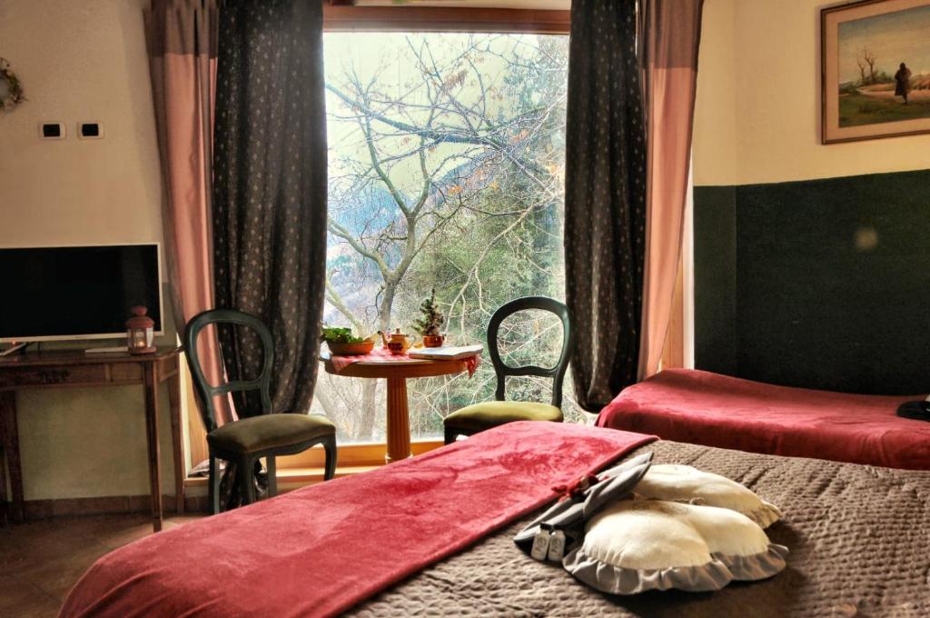 a bedroom with two beds and a table and a window at Villa Amaranta Room and Breakfast in Edolo