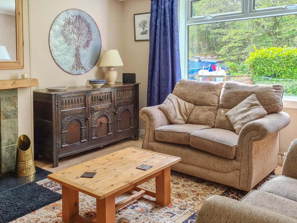 Craik Forestry Cottage في Teviothead: غرفة معيشة مع أريكة وطاولة قهوة