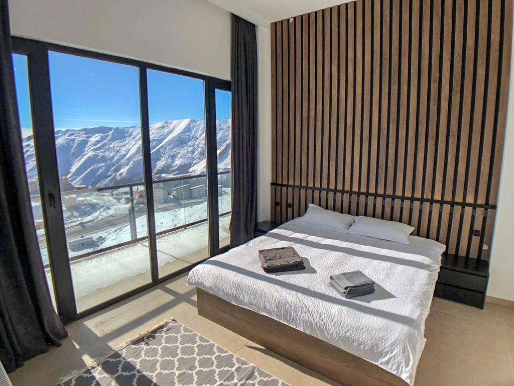 Schlafzimmer mit einem Bett und einem großen Fenster mit Bergblick in der Unterkunft New Gudauri View in Gudauri