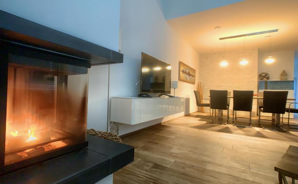 a living room with a fireplace and a table and chairs at Holidayhouse4You in Schwanau