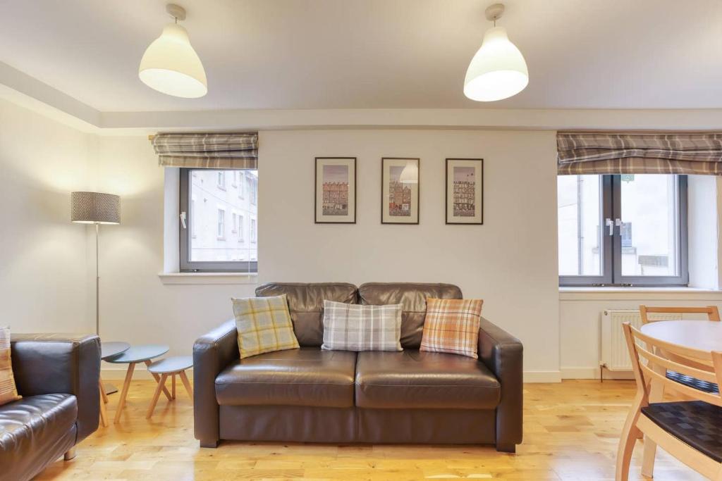 a living room with a leather couch and a table at *Amazing Location!*In heart of the City. 2BR & Cot in Edinburgh