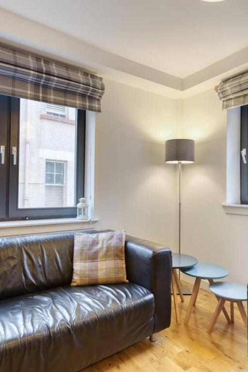a living room with a leather couch and a table at *Amazing Location!*In heart of the City. 2BR & Cot in Edinburgh