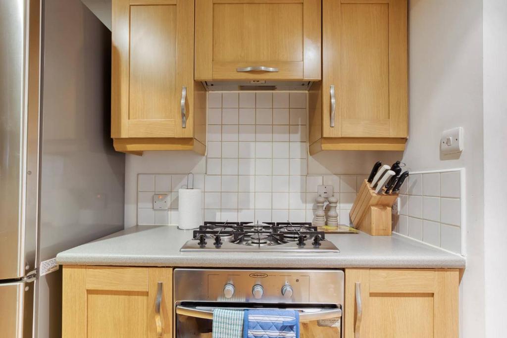 a kitchen with a stove and wooden cabinets at *Amazing Location!*In heart of the City. 2BR & Cot in Edinburgh