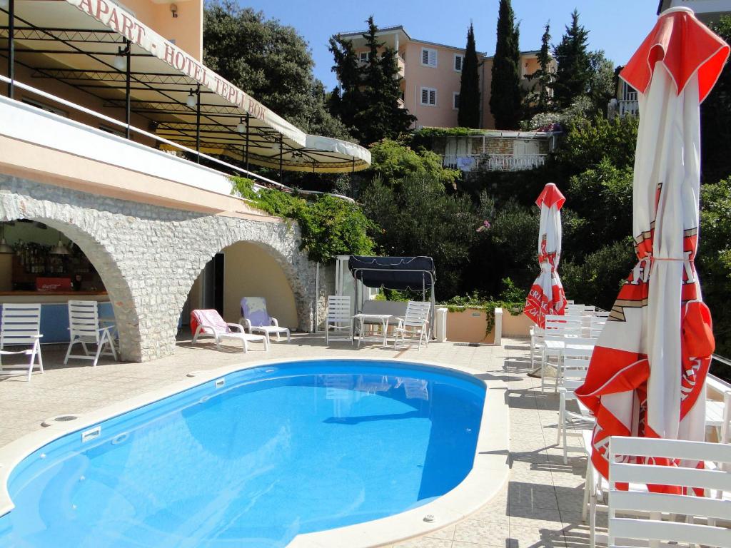 a pool at a hotel with chairs and umbrellas at Apartmani Tepli Bok in Primošten