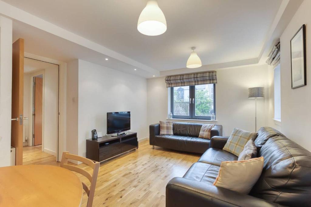 a living room with a leather couch and a table at *Amazing Location!*In heart of the City. 2BR & Cot in Edinburgh