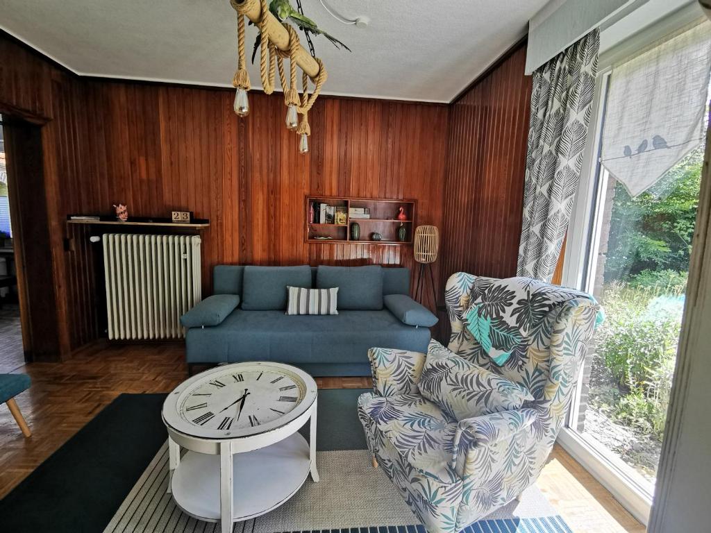 a living room with a blue couch and a clock at HR Townhouse Honigbach in Coesfeld