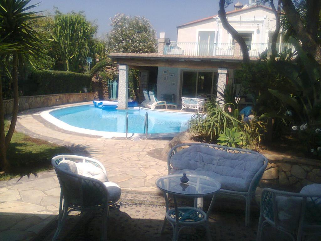 - une piscine avec des chaises et une table en face d'une maison dans l'établissement Villa Lanthana, 2 storeys, detached, à Bari Sardo