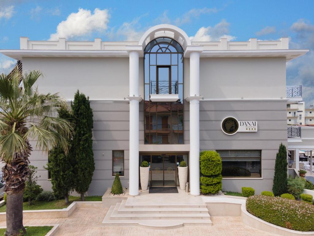 a white building with a palm tree in front of it at Danai Hotel & Spa in Olympiaki Akti