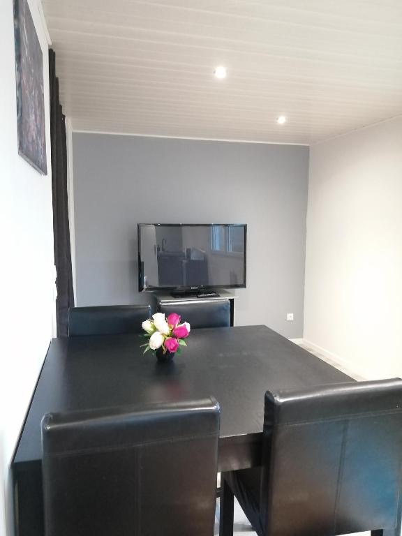 - une table à manger noire avec un vase de fleurs dans l'établissement Quarter Horse 55, à Vadelaincourt