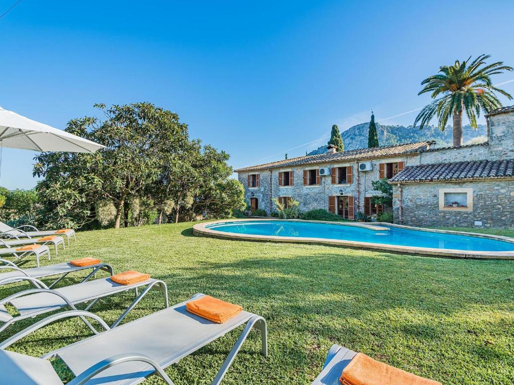 a yard with chairs and a swimming pool in front of a house at Villa Can Fanals by SunVillas Mallorca in Pollença