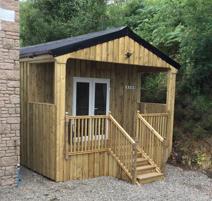 a small wooden shed with a ramp and a porch at Carnach in Fort William