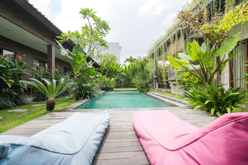 a swimming pool in the middle of a garden with a couch at The Kumpi Bali by The Lavana in Canggu