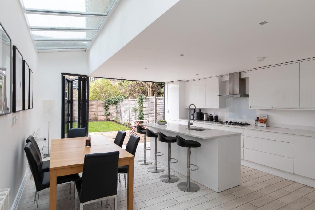 a kitchen with white cabinets and a table and chairs at Stunning double bedroom in 4 bedroom house in Peckam in London