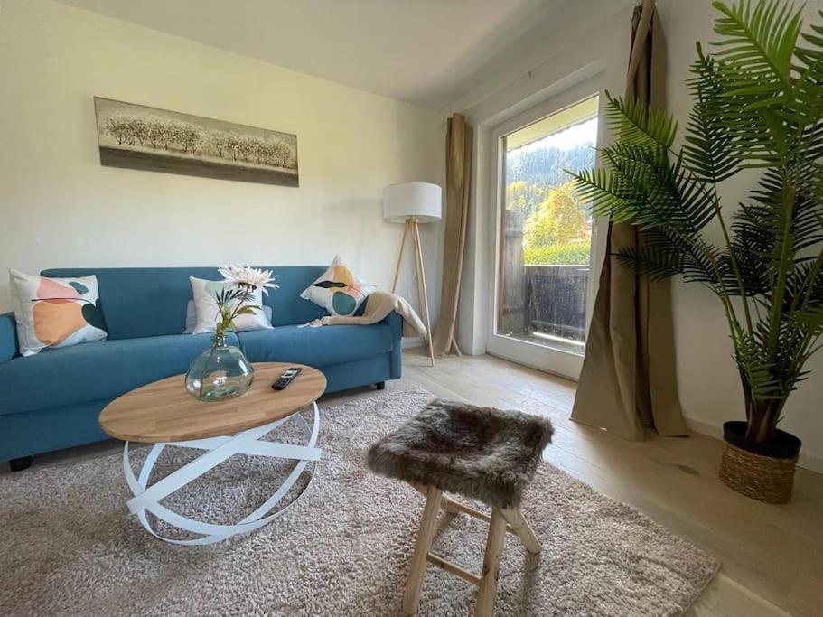 a living room with a blue couch and a table at Großzügige FeWo mit Bergblick am Tegernsee in Bad Wiessee