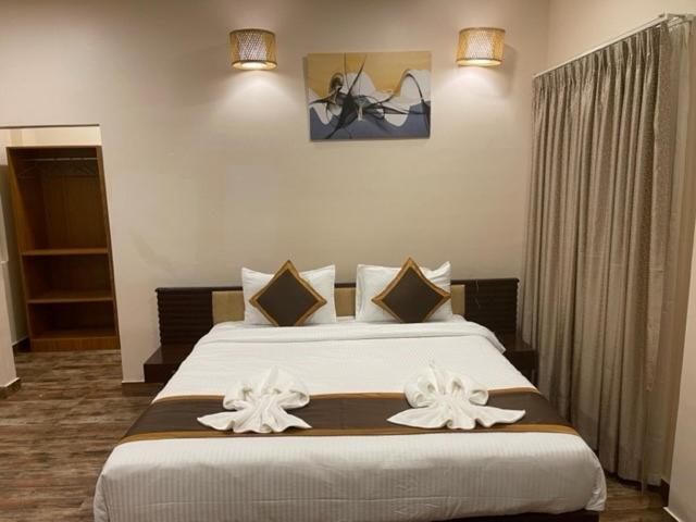 a bedroom with a large bed with two white bows at Jaldapara Forest Tourist Lodge JFTL in Mādāri Hāt