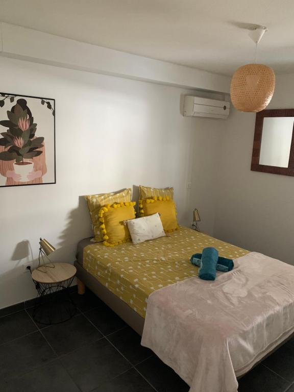 - une chambre avec un lit et des oreillers jaunes dans l'établissement LEU FLAMBOYANT Appartement 2 pièces, à Saint-Leu