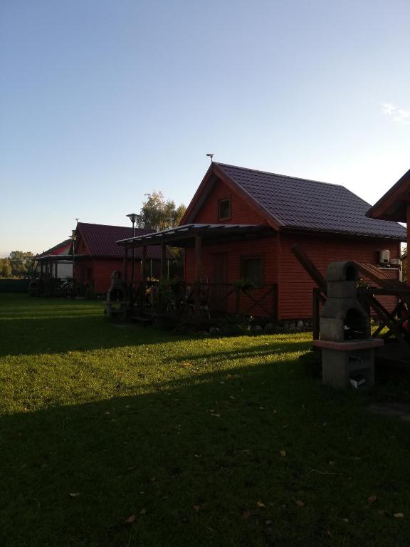 a red house with a yard in front of it at Domki letniskowe Hamer in Łeba
