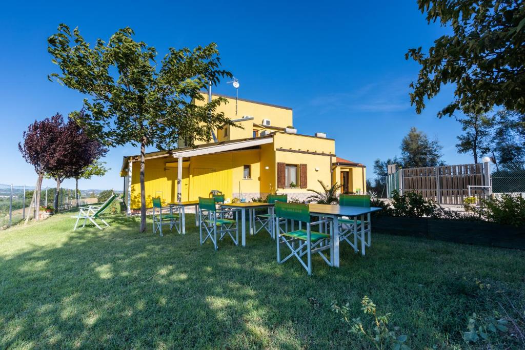 una casa amarilla con mesas y sillas en el patio en La Casa Del Sole en Gradara