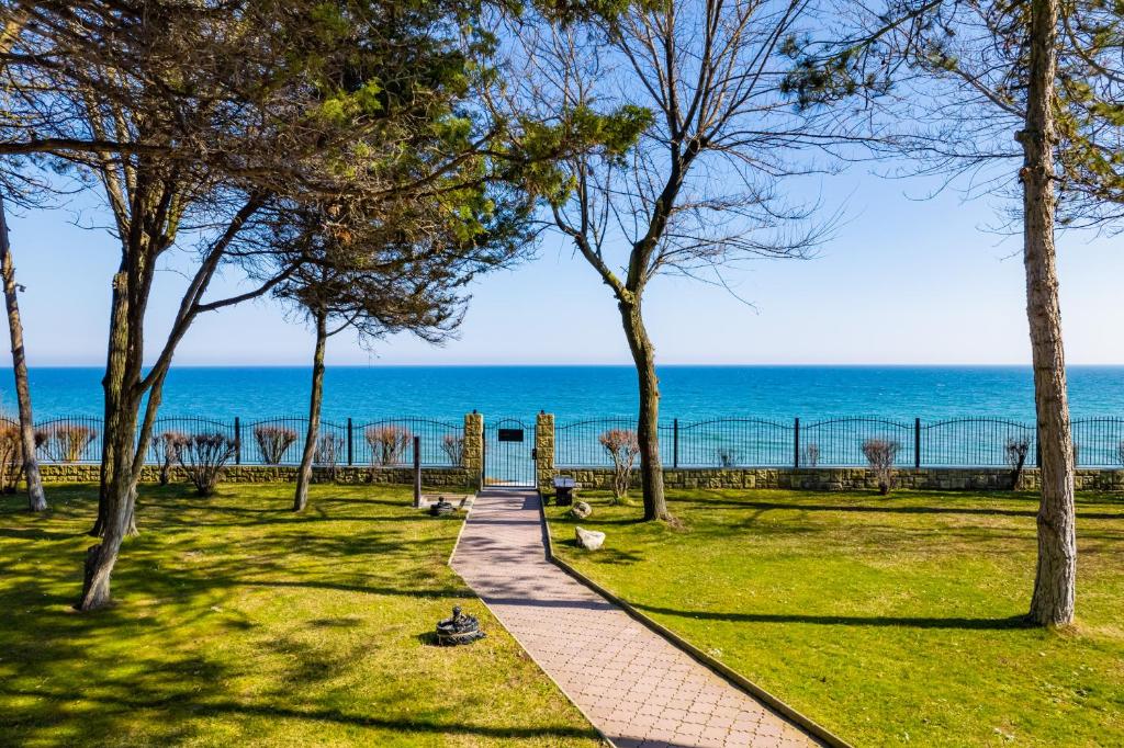 een loopbrug door een park met de oceaan op de achtergrond bij Epico Seafront & Garden Apartments in Olimp