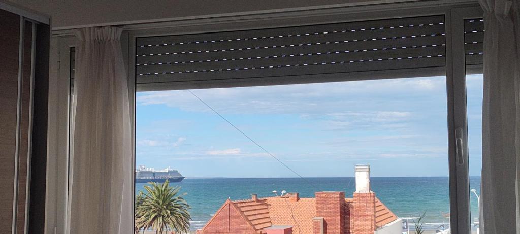 a window with a view of the ocean and a lighthouse at Departamento in Puerto Madryn