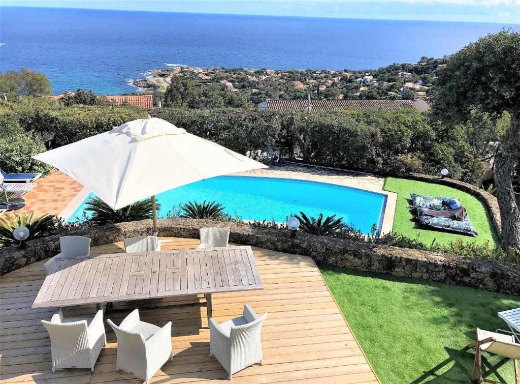 une terrasse avec une table, un parasol et une piscine dans l'établissement Bleu Comme Toit 3425, aux Issambres