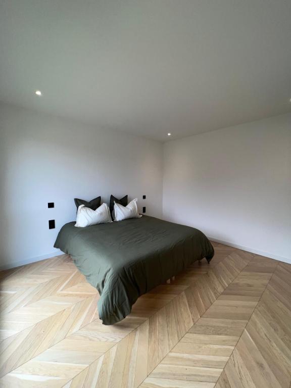 een bed in een witte kamer met een houten vloer bij Les Trois Cyprès in Blois