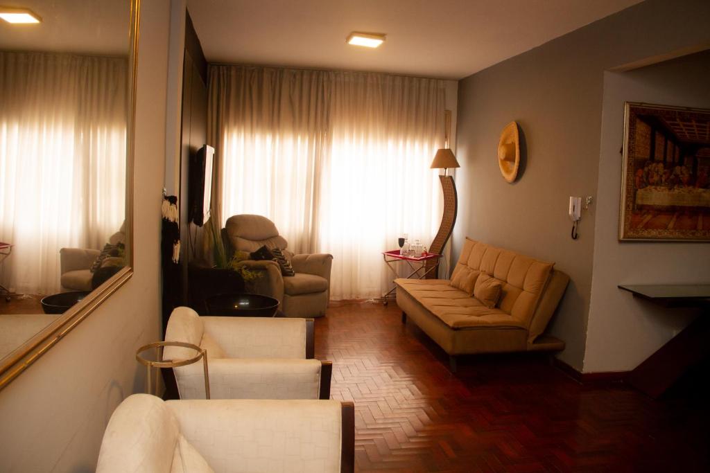 sala de estar con sofá, sillas y ventana en Apartamento Gutierrez 1, en Belo Horizonte