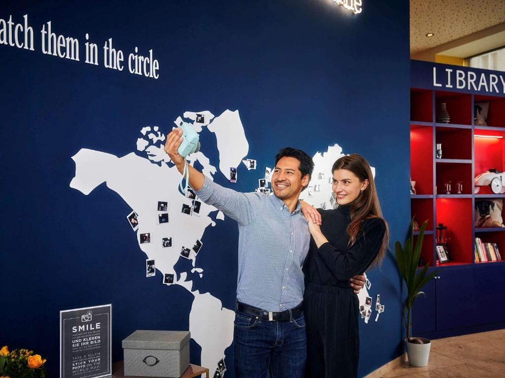 a man and woman standing in front of a world map at Aparthotel Adagio Vienna City in Vienna