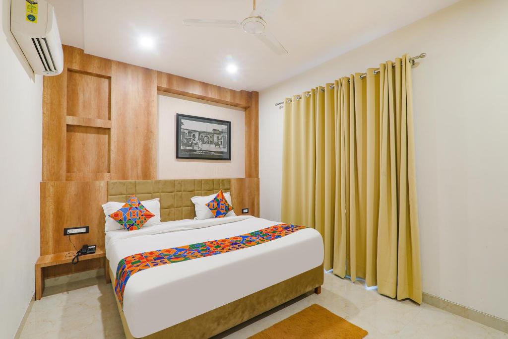 a bedroom with a large bed and yellow curtains at FabHotel The Nawab's in Nalmatha