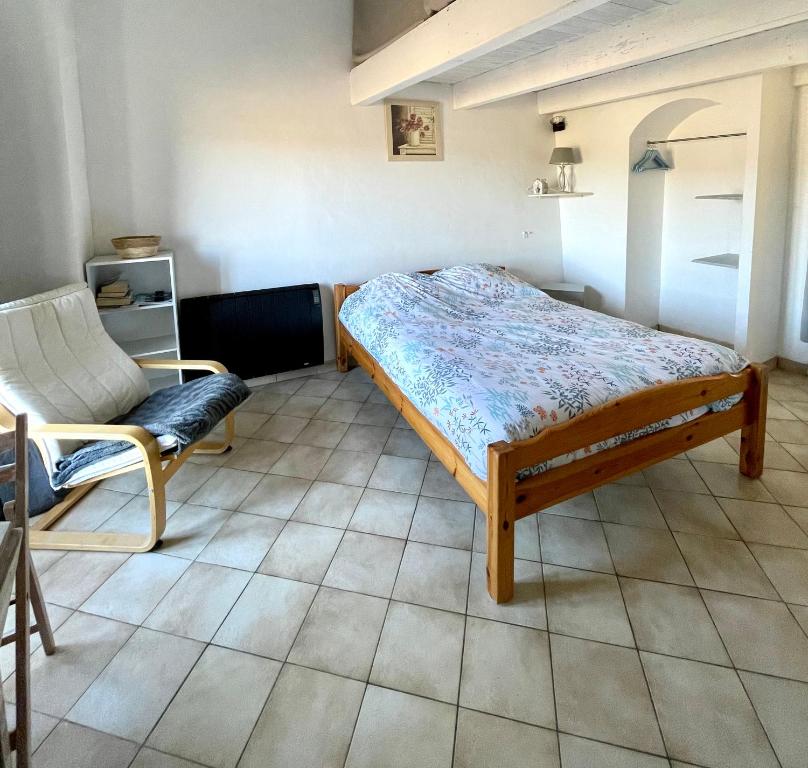 a bedroom with a bed and a chair in it at Le petit chalus in Forcalquier
