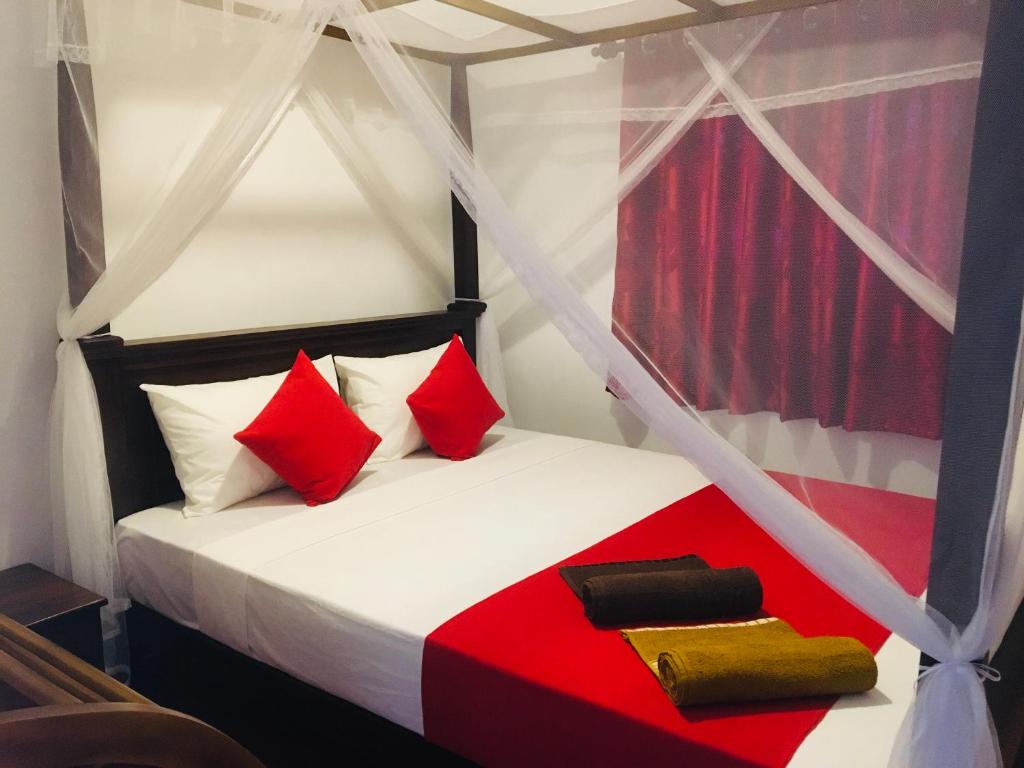 ミリッサにあるCoastal Houseのベッドルーム1室(赤と白の枕が備わるベッド1台付)