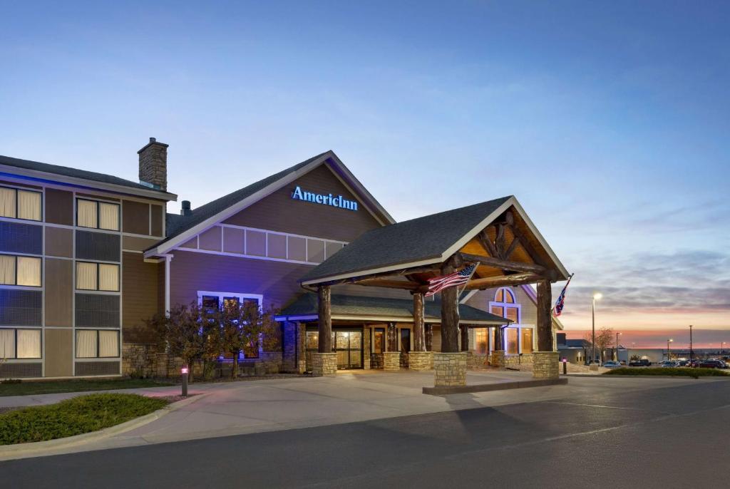 a inn with an american flag in front of a building at AmericInn by Wyndham Laramie Near University of Wyoming in Laramie